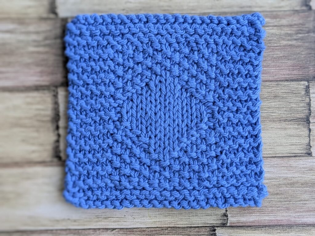 A closer look at the framed border, seed stitch texture, and center diamond.